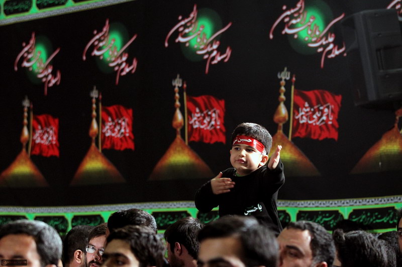 A Shia child mourning for Imam Hossein in front of the Leadership of Iran Imam Khamenei